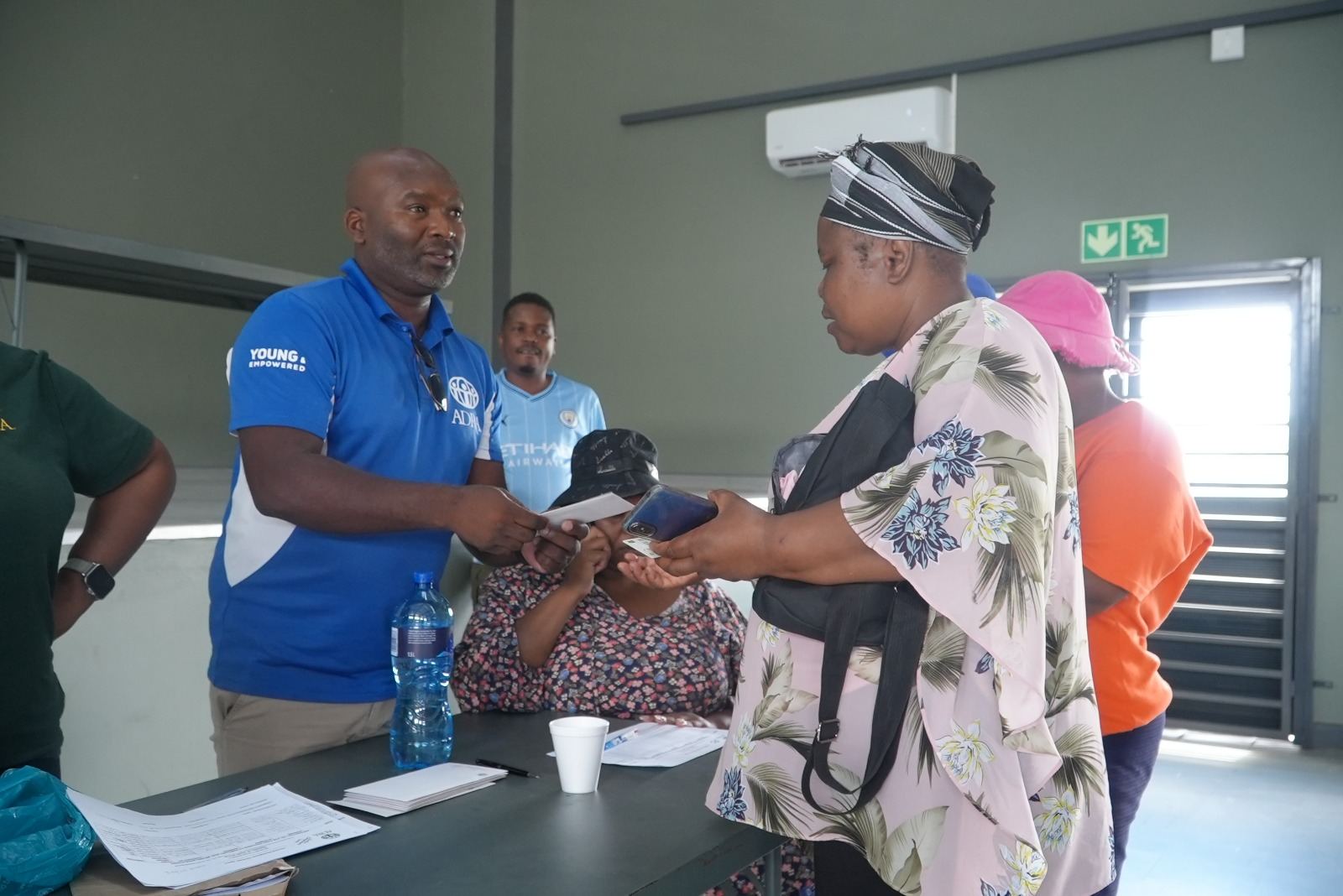 ADRA staff member handing documents to a community member during an assistance process