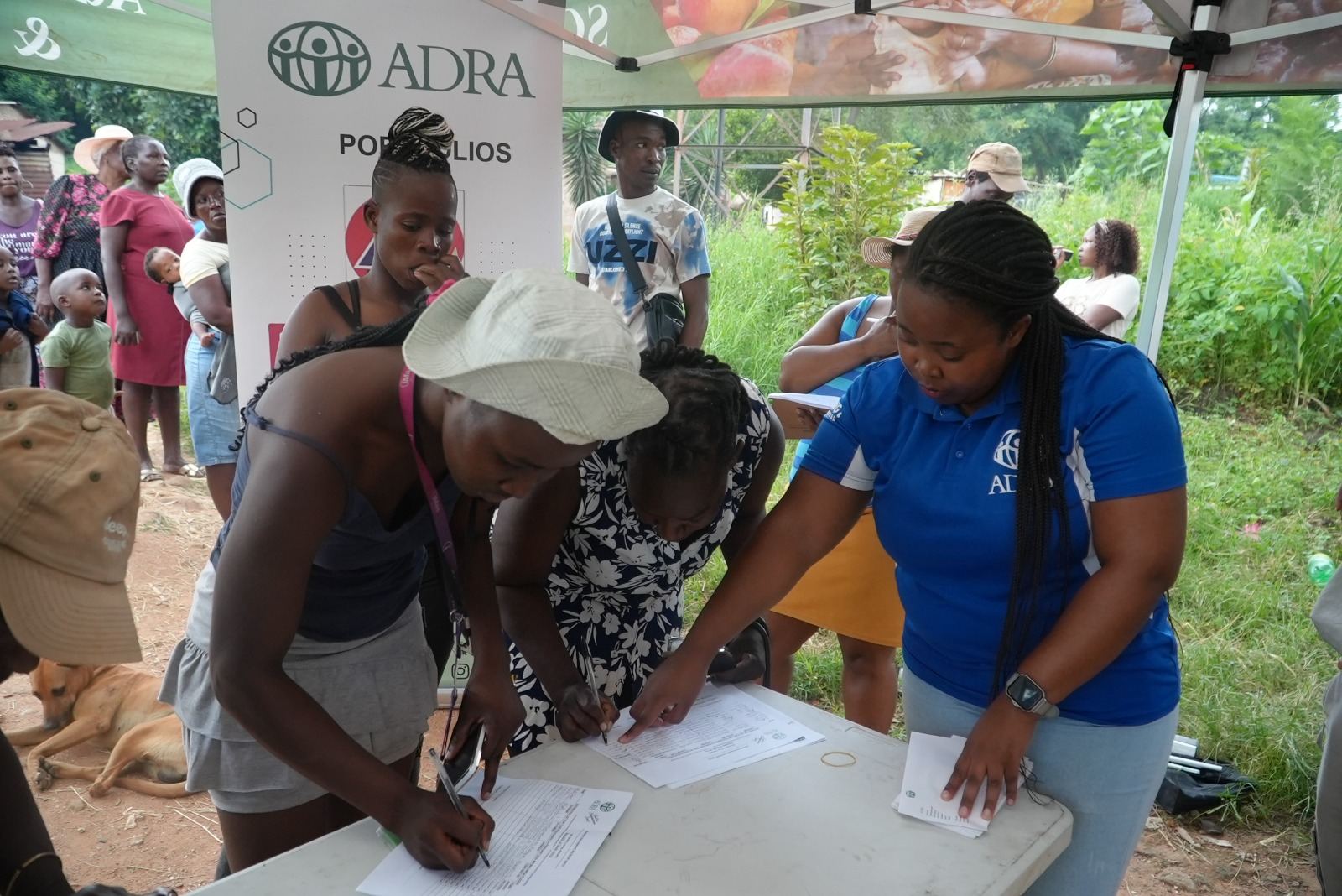 ADRA staff assisting community members at an outdoor outreach table