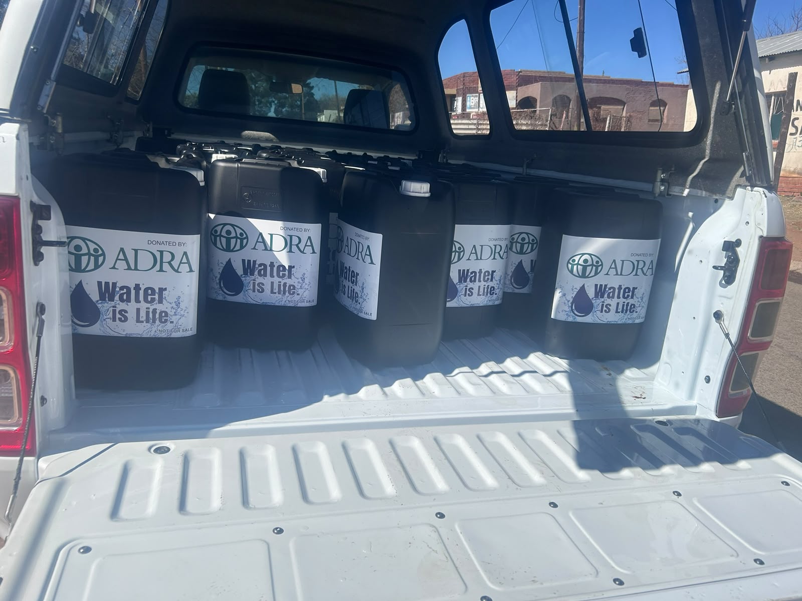 ADRA Water is Life containers loaded in the back of a pickup truck ready for delivery