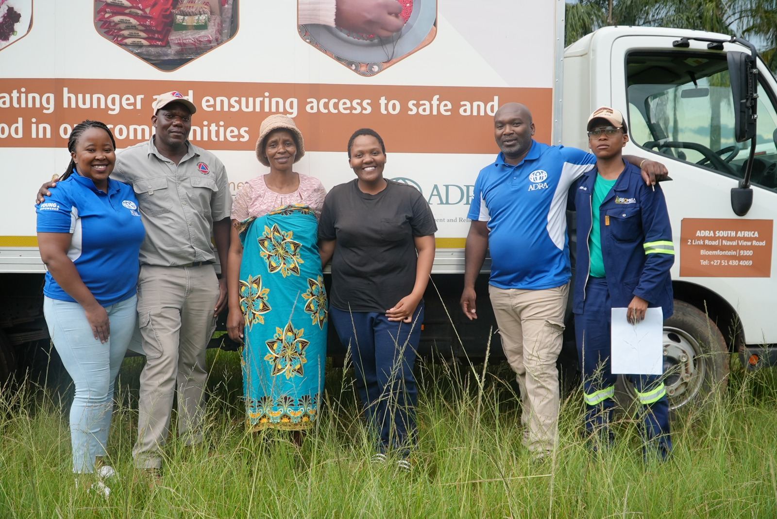 ADRA South Africa team and community partners standing beside a food-security delivery truck